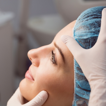 Hands of doctor examining womans face for cosmetic treatment at clinic