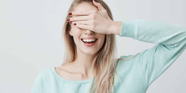 Blog 3 Blonde pretty girl with pure skin, closing her eyes with hand, having happy expression, smiling broadly, anticipating to recieve present from her boyfriend. Fair-haired young woman waiting for pleasant surprise