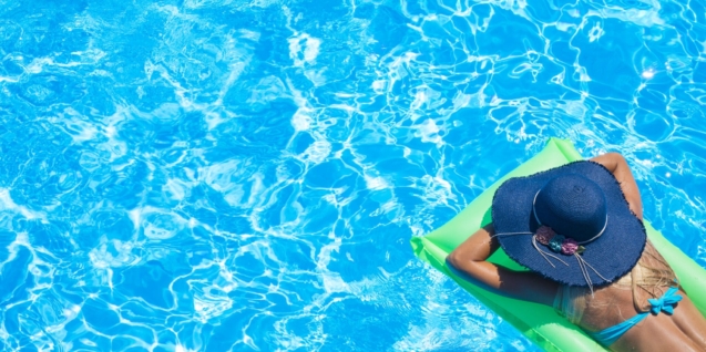 Blog 3 Top view of slim young woman in bikini on the green air mattress in the swimming pool.